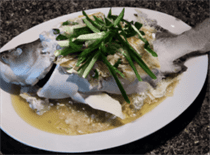 A plate of steamed fish garnished with julienned ginger and scallions